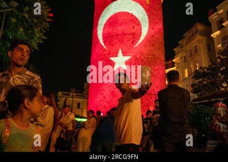 Beyoglu, Istanbul, Turquie. 14 juillet 2023. Un enfant prend une photo de lui-même, devant la Tour Galata avec le drapeau turc projeté sur la Tour pour le 15 juillet, Journée de la démocratie et de l'unité nationale de la Turquie. 14 juillet 2023 (image de crédit : © Tolga Uluturk/ZUMA Press Wire) USAGE ÉDITORIAL SEULEMENT! Non destiné à UN USAGE commercial ! Banque D'Images