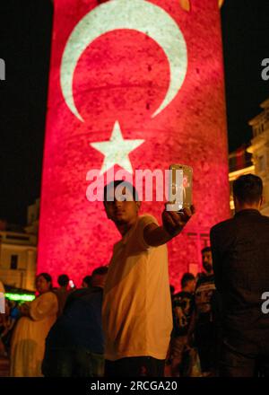 Beyoglu, Istanbul, Turquie. 14 juillet 2023. Un enfant prend une photo de lui-même, devant la Tour Galata avec le drapeau turc projeté sur la Tour pour le 15 juillet, Journée de la démocratie et de l'unité nationale de la Turquie. 14 juillet 2023 (image de crédit : © Tolga Uluturk/ZUMA Press Wire) USAGE ÉDITORIAL SEULEMENT! Non destiné à UN USAGE commercial ! Banque D'Images