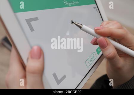 Signature électronique. Femme utilisant stylet et tablette, gros plan Banque D'Images