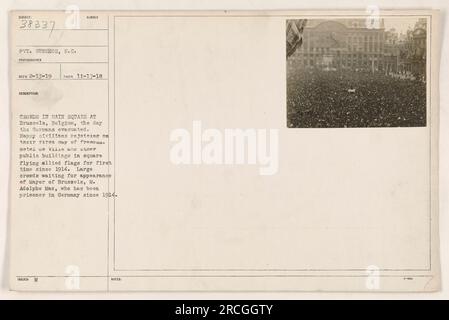 Les foules se rassemblent sur la place principale de Bruxelles, en Belgique, le 17 novembre 1918, alors que les Allemands évacuent. C'est le jour de la libération de la ville, et des civils heureux célèbrent leur liberté retrouvée. L'Hôtel de ville et les autres édifices publics de la place arborent fièrement les drapeaux alliés pour la première fois depuis 1914. La foule attend avec impatience la comparution du maire de Bruxelles, M. Adolphe Max, détenu en Allemagne depuis 1914. Photographie prise par le soldat Gunshor, S.C. le 17 novembre 1918 et recommandée pour reconnaissance le 13 février 1919. Banque D'Images