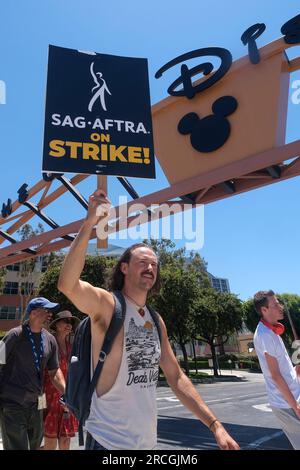 Los Angeles, États-Unis. 14 juillet 2023. Un acteur saisissant marche avec piquet devant le studio Walt Disney Company à Burbank. Jeudi, le Conseil national du syndicat a voté à l'unanimité pour émettre un ordre de grève. L'ordre de grève a pris effet jeudi à minuit, et à partir de vendredi matin, SAG-AFTRA a rejoint les lignes de piquetage avec la Writers Guild of America, qui est dans la 11e semaine de son propre débrayage contre l'Alliance of Motion Picture and Television Producers. (Photo de Ringo Chiu/SOPA Images/Sipa USA) crédit : SIPA USA/Alamy Live News Banque D'Images