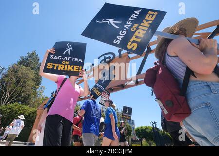 Los Angeles, États-Unis. 14 juillet 2023. Des écrivains et des acteurs frappants marchent avec des piquets devant le studio Walt Disney Company à Burbank. Jeudi, le Conseil national du syndicat a voté à l'unanimité pour émettre un ordre de grève. L'ordre de grève a pris effet jeudi à minuit, et à partir de vendredi matin, SAG-AFTRA a rejoint les lignes de piquetage avec la Writers Guild of America, qui est dans la 11e semaine de son propre débrayage contre l'Alliance of Motion Picture and Television Producers. (Photo de Ringo Chiu/SOPA Images/Sipa USA) crédit : SIPA USA/Alamy Live News Banque D'Images