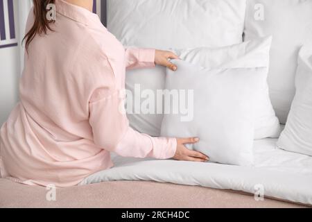 Femme en pyjama faisant le lit à la maison Banque D'Images