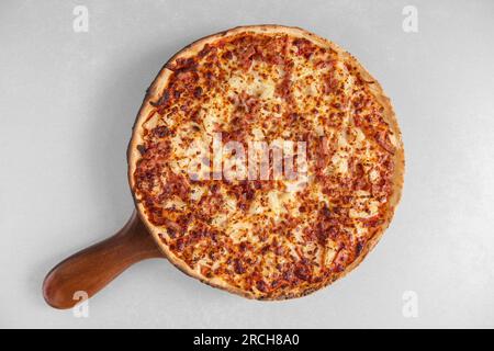 Délicieuse pizza tranchée avec du fromage sur une planche de bois. Fond blanc, vue de dessus Banque D'Images