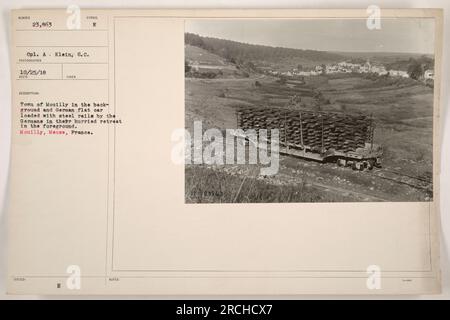 Une voiture plate allemande chargée de rails en acier est vue au premier plan de l'image, prise à Mouilly, Meuse, France. La photo montre les conséquences de la retraite allemande pendant la première Guerre mondiale, avec la ville de Mouilly visible en arrière-plan. Photo prise par le caporal a Klein le 25 octobre 1918. Banque D'Images