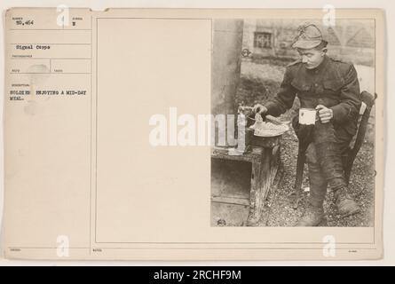 Soldat américain prenant une pause pour manger pendant la première Guerre mondiale Le soldat est vu assis sur le sol, entouré d'herbe et d'arbres. Il est habillé avec désinvolture dans son uniforme, prenant clairement un moment pour déguster de la nourriture avant de retourner à ses fonctions. Banque D'Images