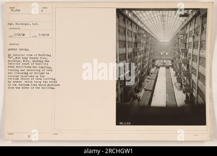 Vue de l'intérieur du bâtiment B de la base d'approvisionnement de la Nouvelle armée à Brooklyn, New York La photographie capture la cour intérieure du bâtiment, montrant les installations pour la manutention, le chargement et le déchargement des voitures et l'élimination du fret à divers endroits. Les grues sont visibles, transportant des matériaux vers des bacs sur les côtés du bâtiment. Photographie prise le 18 juillet 1919 par le sergent Steiniger. Banque D'Images