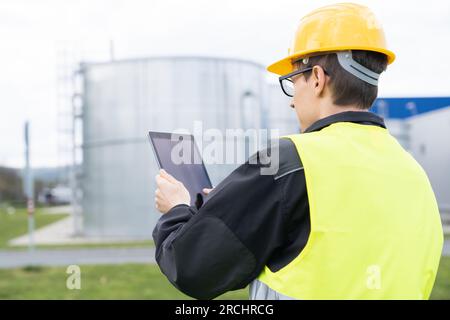 Concevoir avec une tablette numérique sur un fond de réservoirs de gaz. Banque D'Images