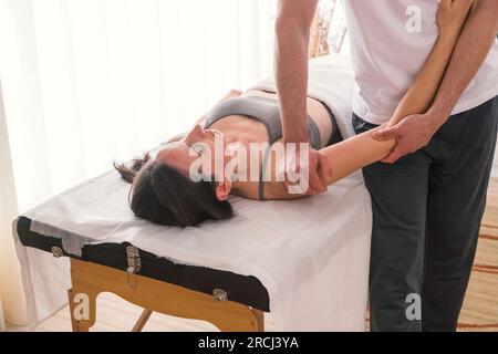 Thérapeute pratiquant la technique de manipulation sur l'humérus. Femme caucasienne traitée par un thérapeute pour aider à soulager la douleur ou améliorer la condition physique Banque D'Images
