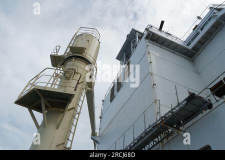 Partie arrière de la superstructure blanche et grue à cargaison crème du porte-conteneurs observés depuis le pont principal. Banque D'Images