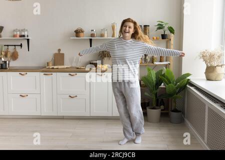 Femme heureuse dans les vêtements décontractés à la maison dansant dans la cuisine Banque D'Images
