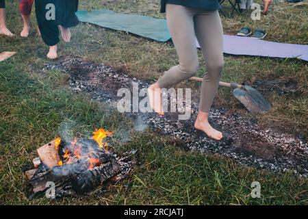 Marche au charbon ou marche au feu. Personne pieds nus sur du bois brûlé et des braises chaudes. Entraînement de la volonté et de la force pour la guérison. initiation et foi Banque D'Images