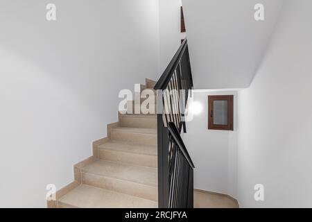 Bel escalier confortable avec une piste beige, des balustrades en métal noir et des murs blancs dans un nouveau bâtiment dans une nouvelle zone urbaine confortable. CopySpace Banque D'Images