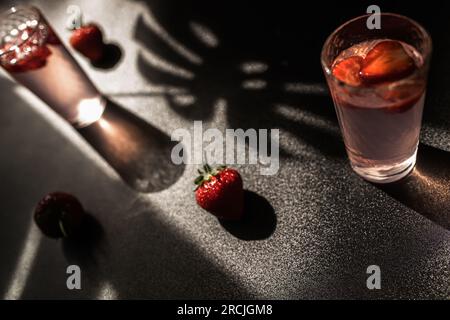 Cocktail de fraises en été. Un mélange rafraîchissant de fraises, de glaçons et d'une touche de menthe. verre sur fond sombre, parfait pour une fête ou un Banque D'Images