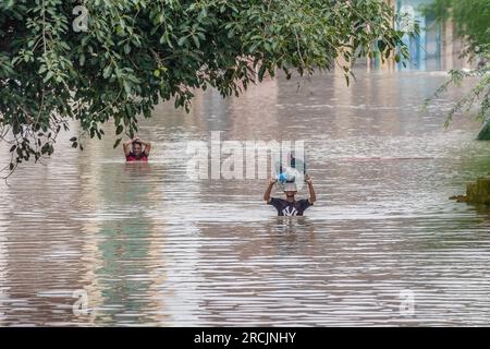 New Delhi, Inde. 14 juillet 2023. Un garçon pataugeait dans une rue inondée après une élévation du niveau de l'eau de la rivière Yamuna suite à de fortes pluies de mousson à New Delhi. Le gouvernement a émis des avertissements concernant des conditions semblables à des inondations et a demandé aux personnes vivant dans le lit de la rivière ou dans les zones basses d'évacuer leurs maisons. Crédit : SOPA Images Limited/Alamy Live News Banque D'Images