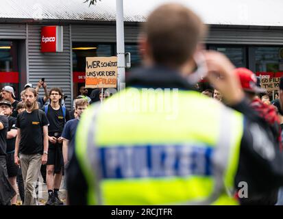 15 juillet 2023, Rhénanie du Nord-Westphalie, Herford : un participant à la manifestation porte une affiche avec l'inscription : «qui nous protège de la police». Selon la police, une personne privée a enregistré la manifestation sous le titre "contre la violence policière raciste". Le contexte est un incident survenu en juin, lorsqu'un jeune de 19 ans a été grièvement blessé après une poursuite. La police avait tiré 34 coups de feu, comme Reul (CDU), ministre de l'intérieur de Rhénanie-du-Nord-Westphalie, l'a récemment décrit devant la commission de l'intérieur du Parlement de l'État. Photo : Guido Kirchner/dpa Banque D'Images