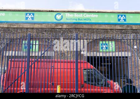 Un homme en chapeau melon noir assis sur la clôture à côté d'un van rouge devant la station d'essai mot attendant d'être servi Londres Angleterre Royaume-Uni Banque D'Images