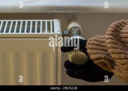 Main dans les gants et le pull d'hiver épais contrôle la soupape de gaz naturel. Banque D'Images