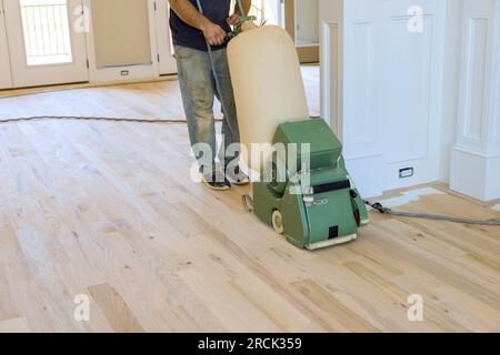 Charpentier meulant parquet en bois en utilisant une ponceuse de sol une maison nouvellement construite Banque D'Images