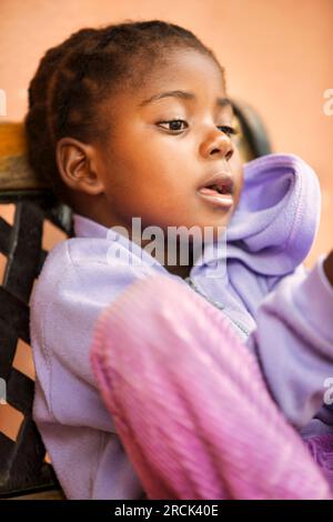 portrait d'une fille africaine de village avec des tresses placées sur le banc devant la maison Banque D'Images