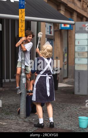 Kaiserslautern, Allemagne. 15 juillet 2023. Le jeune garçon fait partie du spectacle de rue 'Die Zimmermädchen' de Blaumeier. Trois jours de spectacles de rue théâtraux et de musique offerts par 200 artistes internationaux dans le centre-ville de Kaiserslautern - jour 2. Crédit : Gustav Zygmund/Alamy News Banque D'Images