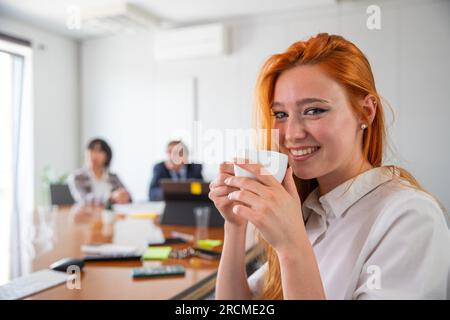 Une femme d'affaires se détend dans le bureau en buvant du café, le concept de bien-être au travail Banque D'Images