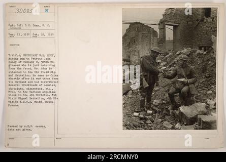 Sgt. 1 cl. C.E. Dunn, 8. C., est vu sur la photo donnant de la gomme au soldat John Roney de la compagnie D, 305th Engineers. Y.M.C.A. Secrétaire W.H. Eddy est également présent, distribuant des biscuits, du chocolat et des cigarettes à divers organismes de la 4e Division. La photo a été prise à Cuisy, Meuse, France, après avoir été libérée des Allemands. La date d'approbation du censeur est inconnue. Banque D'Images