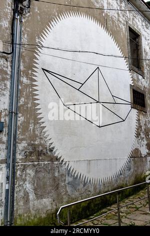 Peinture murale d'un bateau en papier sur un mur par un magasin louant des bateaux et des canoës, Gaia, Porto, Portugal Banque D'Images