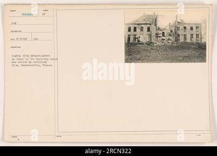 Enchevêtrements de fils barbelés devant un bâtiment endommagé par des tirs d'artillerie à Goussanville, en France. La photographie a été prise par le photographe 59880 du SUNBER G-2 le 12 mai 1919. La description note la présence du symbole 'eu' et souligne les enchevêtrements de fils barbelés. Banque D'Images