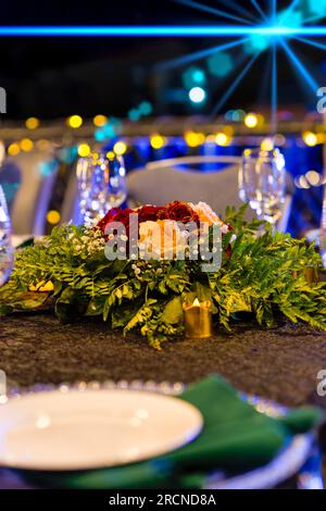 Arrangement floral de table, bouquet de roses rouges et blanches avec paillettes dorées. Banque D'Images