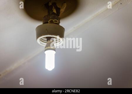 Danger : vieille ampoule fluocompacte avec fils exposés, risque d'incendie et d'électrocution Banque D'Images