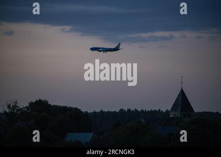 Steenokkerzeel, Belgique. 15 juillet 2023. L'illustration montre un avion survolant l'église de Humelgem, Steenokkerzeel, près de l'aéroport de Bruxelles de nuit, à Zaventem, samedi 15 juillet 2023. Le ministre fédéral de la mobilité Gilkinet (Ecolo) a présenté cette semaine un projet de décret ministériel visant à limiter les nuisances sonores pour les résidents vivant à proximité de l’aéroport internatinoal. Une mesure frappante est l'interdiction totale des vols de nuit à partir de 11 heures et 6 heures du matin BELGA PHOTO NICOLAS MAETERLINCK crédit : Belga News Agency/Alamy Live News Banque D'Images