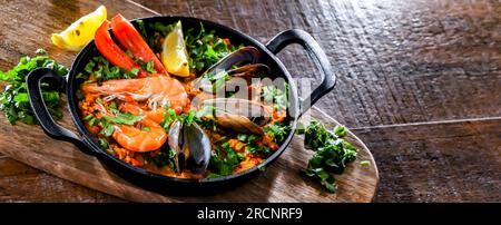 Paella de fruits de mer servie dans une poêle en fonte. Banque D'Images