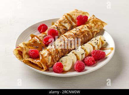 crêpes fraîchement cuites avec fruits et sauce caramel sur table blanche Banque D'Images
