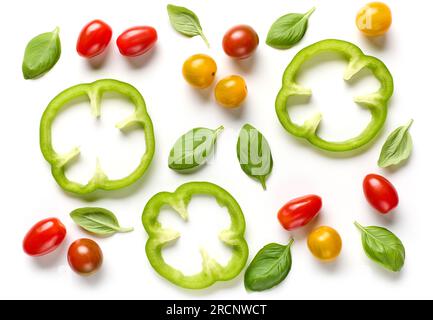 composition à plat de tranches de paprika vert, tomates colorées et feuilles de basilic isolées sur fond blanc, vue de dessus Banque D'Images