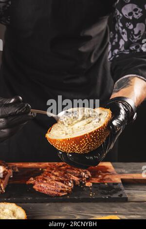 Cuire préparer un steak Burger en ajoutant la sauce. Le processus de fabrication d'un hamburger. Banque D'Images