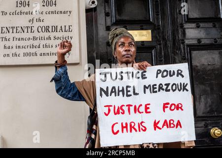 Londres, Royaume-Uni. 14 juillet 2023. Marcia Rigg de United Families & Friends Campaign (UFFC) tient une pancarte à l'entrée de l'ambassade de France à Londres pendant la manifestation. Merzouk, 17 ans, a été abattu par un policier lors d'un arrêt de circulation le 27 juin dans la banlieue parisienne de Nanterre, sa mort a donné lieu à des manifestations où des symboles de l'Etat tels que des mairies, des commissariats et d'autres bâtiments ont été attaqués. La protestation de Justice for Nahel UK, BLM UK et des militants à travers le Royaume-Uni était d'exprimer leur solidarité avec la campagne Justice pour Nahel. Crédit : SOPA Images Limited/Alamy Live News Banque D'Images