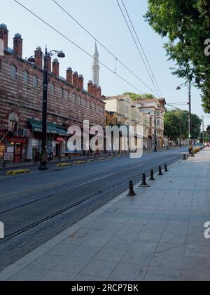 Rue presque vide avec des boutiques de souvenirs un matin d'été à Istanbul, en Turquie, avec un minaret dominant les shpps Banque D'Images