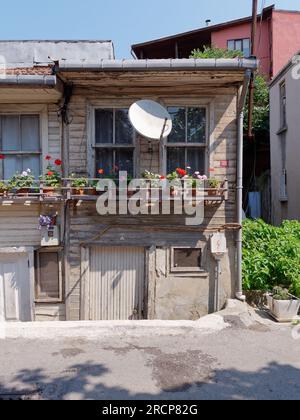 Maison délabrée mais pittoresque à Anadolu avec un rebord de fenêtre en bois plein de pots de fleurs et une antenne parabolique au-dessus. Istanbul, Turquie Banque D'Images