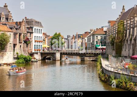 Gand, Belgique - 10 juillet 2010 : Rivière et ponts de Gand, petits bateaux à moteur passant sous Vleeshuisbrug (pont) sur la rivière Leie par une journée ensoleillée. Banque D'Images