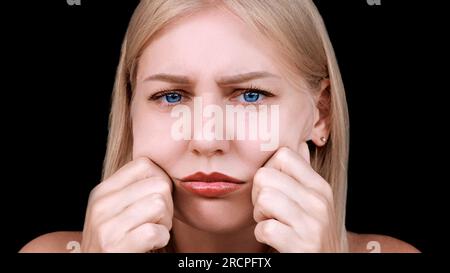 Deuxième menton, obésité. Portrait d'une femme de 30 ans tirant la peau sur son menton regarde dans l'appareil photo avec un aspect frustré. Problèmes de Banque D'Images