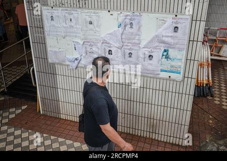 Hong Kong, Chine. 16 juillet 2023. Un homme regarde les profils des activités politiques recherchées sur un tableau d'affichage dans Wah Fu Estate. Les forces de police de Hong Kong recherchaient huit militants politiques de Hong Kong vivant à l'étranger le 3 juillet 2023. Un total de huit personnes, à savoir Yam Kevin, Yuan Gong-yi, Kwok Fung-yee, Kwok Wing-Hang, Hui Chi-fung, Mung Siu-tat, Lau Cho-dik et Law Kwun-chung. Après que la police de Hong Kong ait annoncé cela, ils ont mis les avis de recherche dans de nombreux lieux publics à Hong Kong. Crédit : SOPA Images Limited/Alamy Live News Banque D'Images