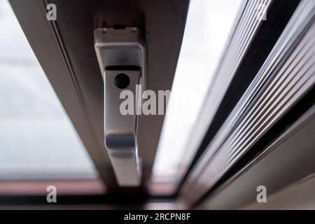 Poignée en aluminium argenté sur la fenêtre fermée avec système de blocage avec arrière-plan flou. Gros plan au-dessus de la poignée avec mécanisme de verrouillage sécurisé. Banque D'Images