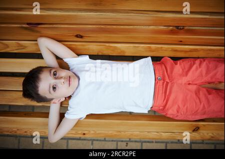 Vue d'en haut d'un adorable écolier intelligent, beau petit garçon caucasien 9 ans, habillé en blanc décontracté maquette t-shirt et jaune sh Banque D'Images