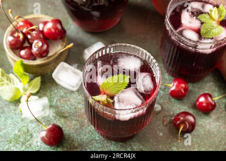 Cola de cerise rafraîchissante froide dans un verre avec de la glace sur un fond de pierre, jus d'été. Banque D'Images