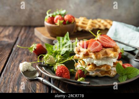 Gaufres belges maison avec fraises berrie fraîches et ricotta pour le petit-déjeuner sur une table rustique. Espace de copie. Banque D'Images