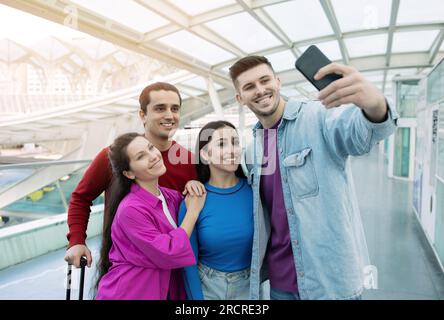 Groupe de deux couples romantiques posant dans l'aéroport faisant Selfie Banque D'Images