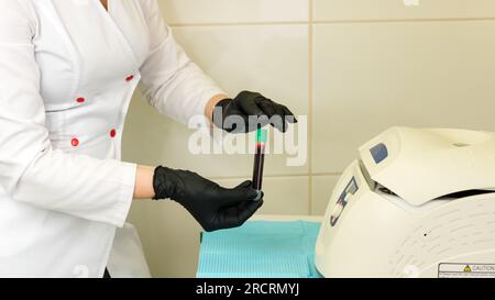 Сosmetologist tient le tube à essai avec le sang devant la centrifugeuse. Stade de réception de plasma riche en plaquettes pour la procédure de traitement PRP et plasma lift tre Banque D'Images