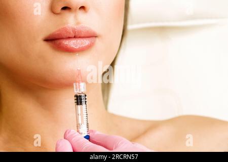 Cosmétologue fait des injections pour l'augmentation des lèvres belle femme. Augmentation labiale par l'acide hyaluronique en clinique de beauté. Gros plan Banque D'Images