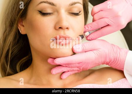 Esthéticienne fait des injections pour l'augmentation des lèvres belle femme. Augmentation labiale par l'acide hyaluronique en clinique de beauté. Banque D'Images